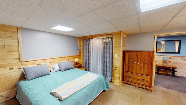 bedroom featuring a drop ceiling and wood walls