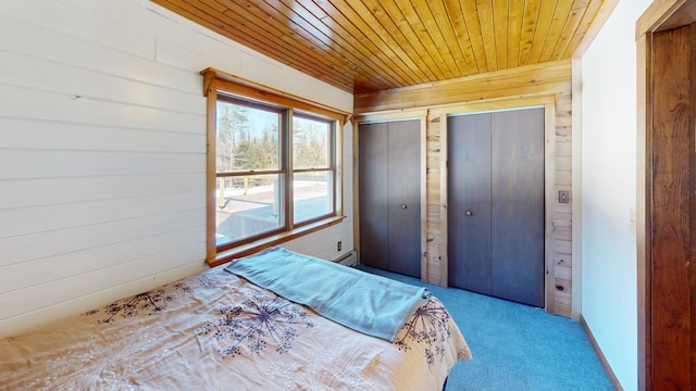 unfurnished bedroom featuring light carpet, wood ceiling, wooden walls, and two closets