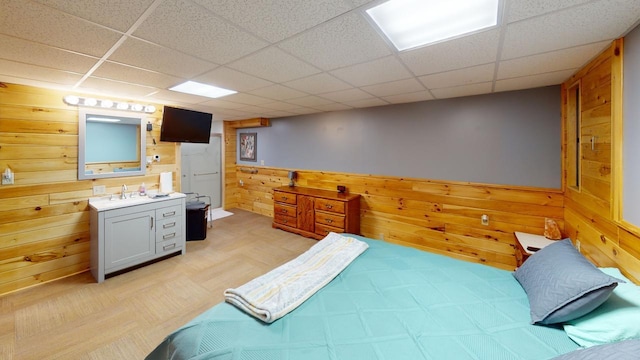 bedroom featuring a drop ceiling and wood walls