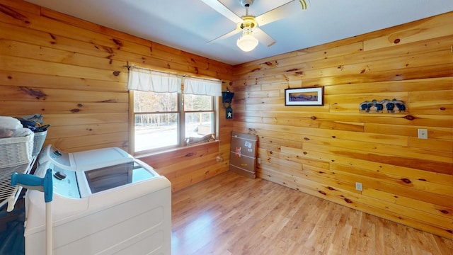 laundry area with ceiling fan, light hardwood / wood-style flooring, washer and dryer, and wooden walls