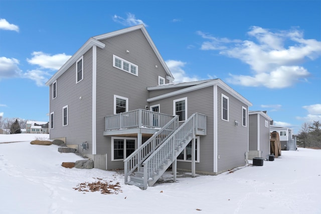 snow covered back of property with a deck