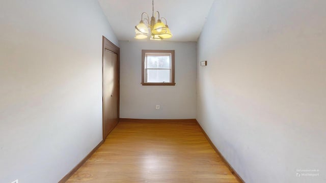 corridor featuring an inviting chandelier and light hardwood / wood-style floors