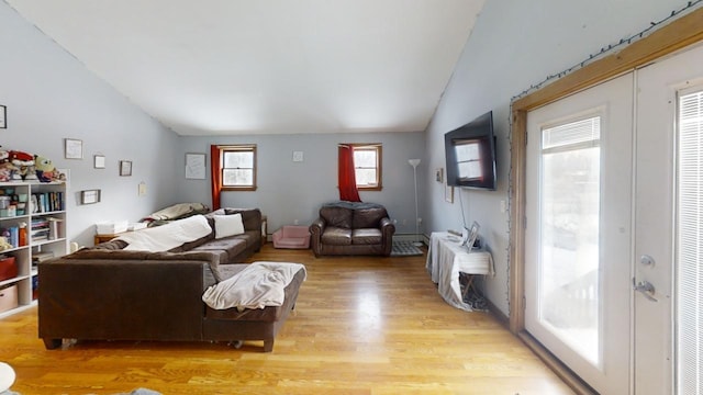 living room with french doors, light hardwood / wood-style floors, and vaulted ceiling