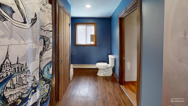 bathroom with wood-type flooring, baseboard heating, and toilet