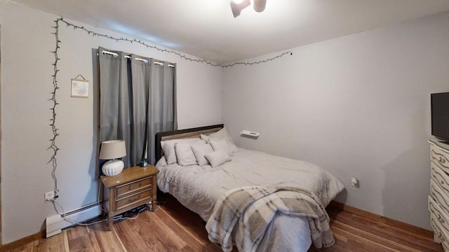 bedroom featuring hardwood / wood-style flooring and a baseboard heating unit