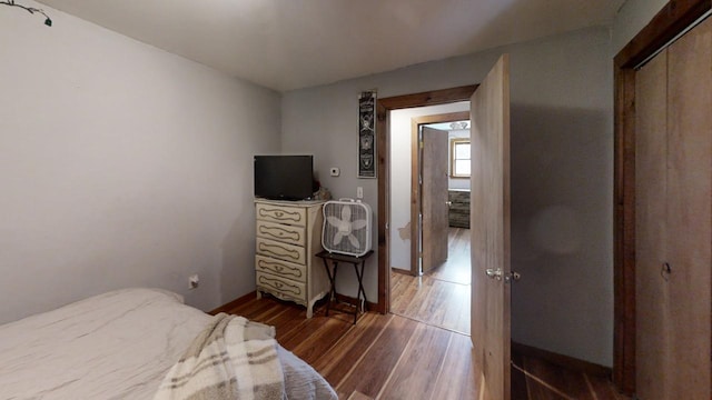 bedroom with dark hardwood / wood-style floors and a closet