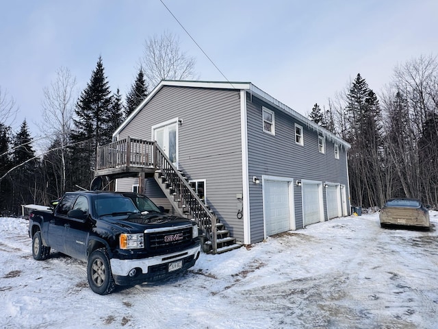 view of snowy exterior featuring a wooden deck and a garage