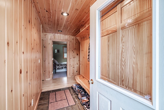 mudroom featuring dark tile patterned floors, wooden ceiling, and wood walls