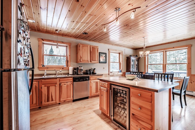 kitchen with sink, dishwasher, hanging light fixtures, a kitchen island, and beverage cooler