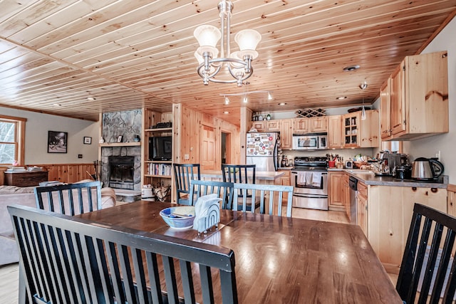 dining space with sink, a fireplace, wood ceiling, and light hardwood / wood-style floors