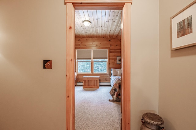 hallway featuring a baseboard heating unit, wooden walls, wooden ceiling, and carpet