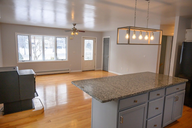 kitchen with black refrigerator, decorative light fixtures, dark stone countertops, a center island, and baseboard heating