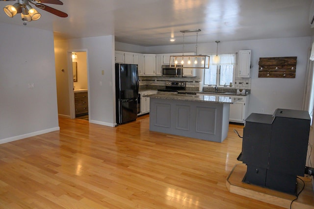 kitchen featuring a kitchen island, appliances with stainless steel finishes, pendant lighting, white cabinetry, and decorative backsplash