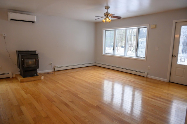 unfurnished living room featuring a baseboard heating unit, light hardwood / wood-style floors, an AC wall unit, and a wood stove