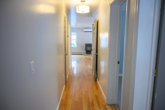 hallway featuring a baseboard radiator, a wall mounted AC, and light hardwood / wood-style floors