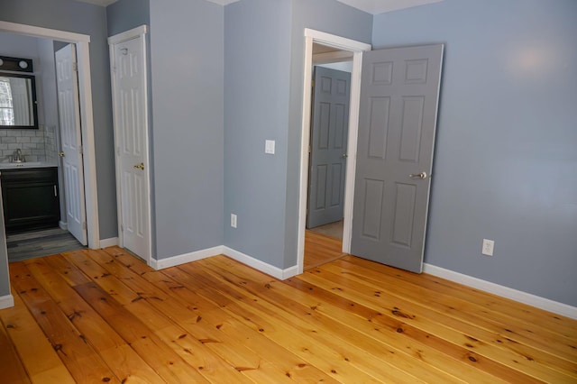 unfurnished bedroom with ensuite bathroom, sink, and light hardwood / wood-style flooring