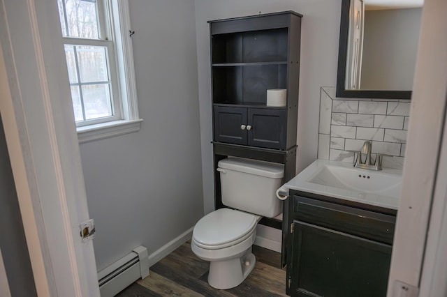 bathroom featuring a baseboard radiator, wood-type flooring, decorative backsplash, vanity, and plenty of natural light