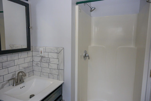 bathroom with walk in shower, vanity, and backsplash