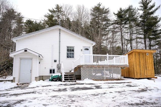 snow covered back of property with a deck