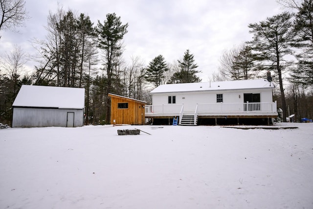 snow covered house with an outbuilding and a deck