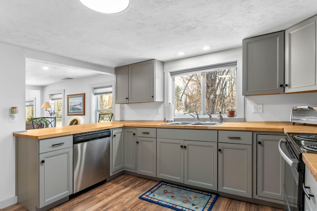 kitchen with butcher block countertops, sink, gray cabinets, dishwasher, and range with electric stovetop