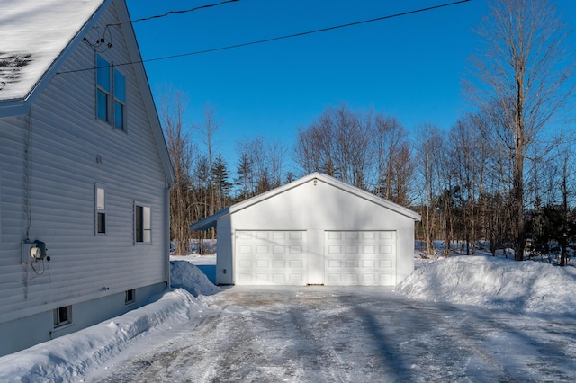 view of snow covered exterior featuring a garage and an outdoor structure