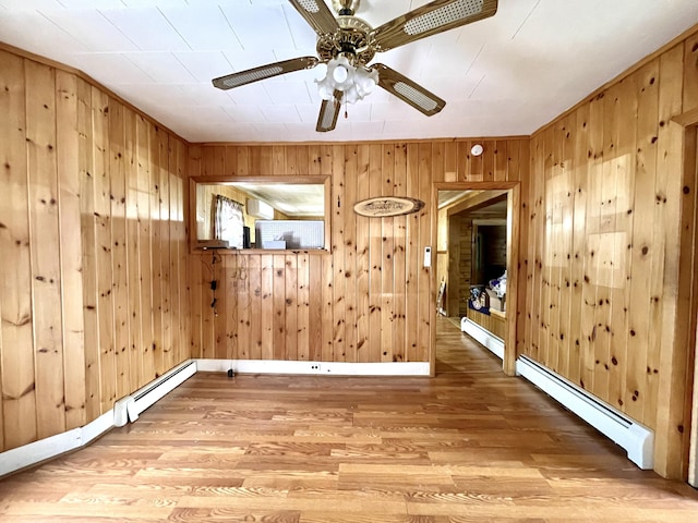 empty room with wood-type flooring, wood walls, and baseboard heating