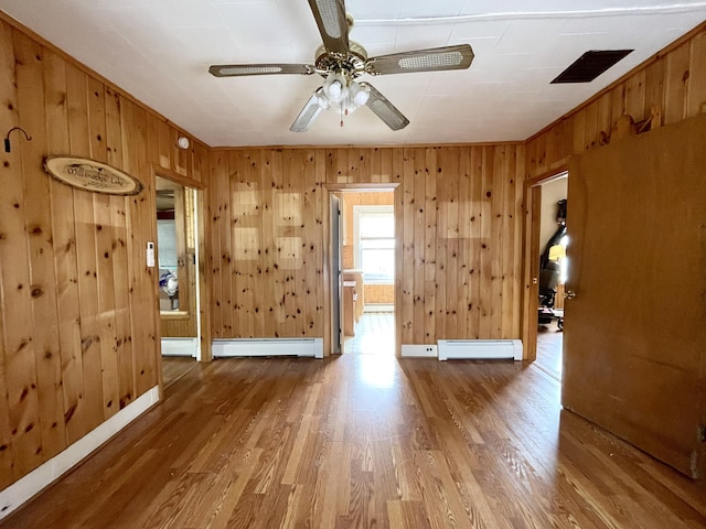 unfurnished room with ceiling fan, a baseboard radiator, and wood-type flooring