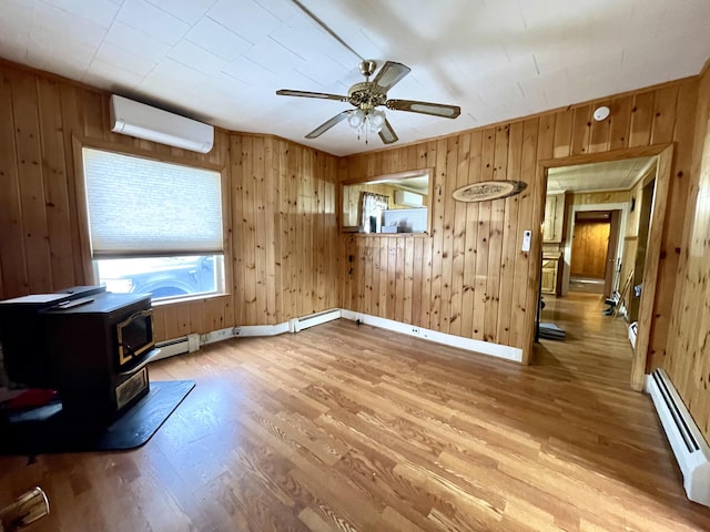 interior space with baseboard heating, ceiling fan, a wall unit AC, and a wood stove