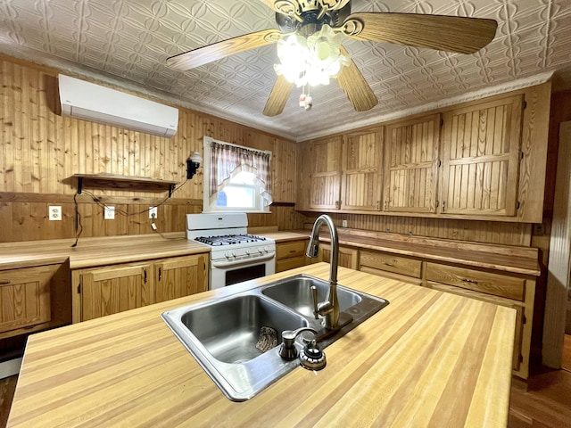 kitchen with an AC wall unit, white range with gas cooktop, sink, and ceiling fan