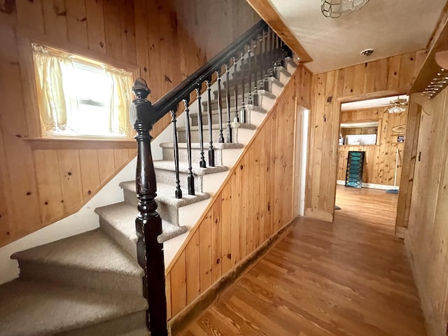 stairway with hardwood / wood-style floors and wood walls