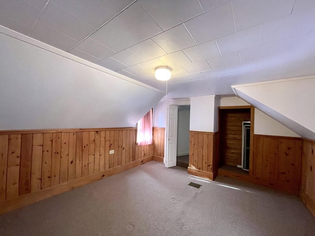 bonus room featuring lofted ceiling, light carpet, and wood walls