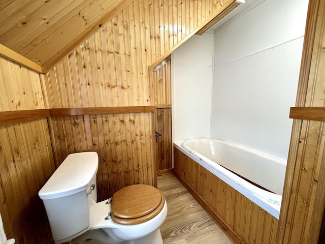 bathroom with wooden walls, wood-type flooring, toilet, and vaulted ceiling