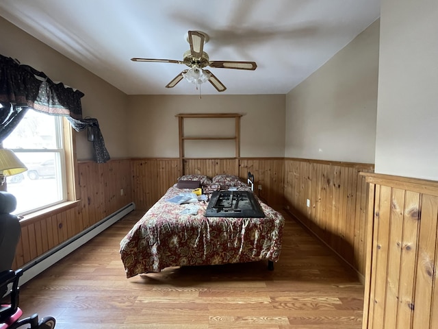 bedroom featuring wood-type flooring, ceiling fan, and a baseboard radiator