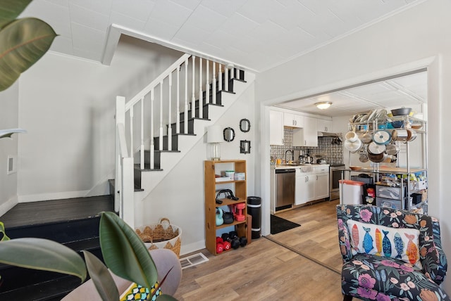 staircase with hardwood / wood-style floors, ornamental molding, and sink