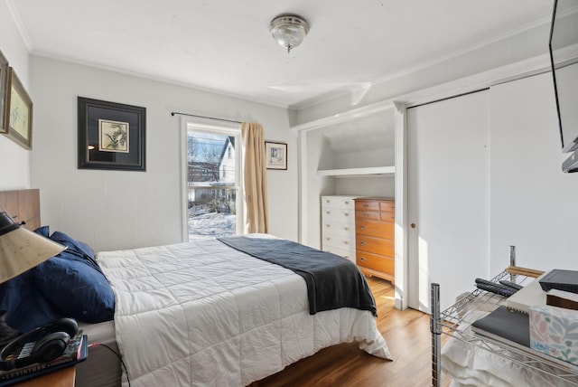 bedroom featuring hardwood / wood-style flooring, crown molding, and a closet