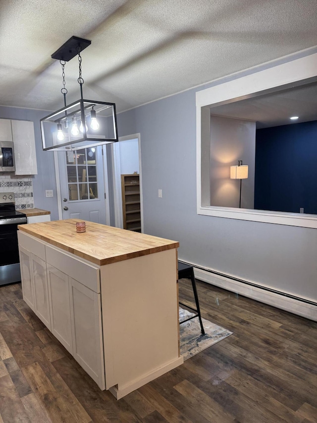 kitchen featuring butcher block countertops, white cabinetry, hanging light fixtures, stainless steel appliances, and a kitchen island