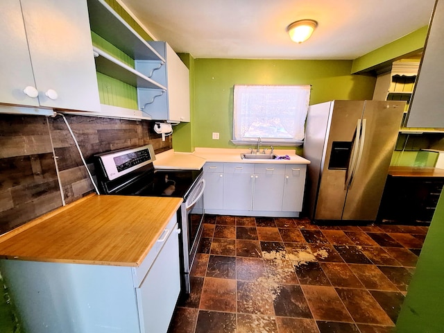 kitchen with appliances with stainless steel finishes, sink, white cabinets, and backsplash