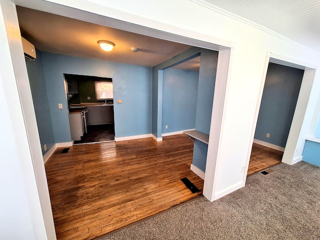 unfurnished room featuring dark colored carpet, a wall mounted AC, and crown molding