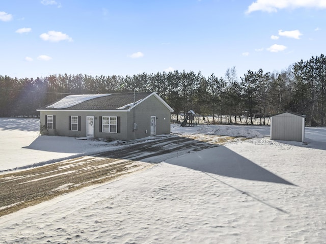 rear view of property featuring a storage shed and a playground