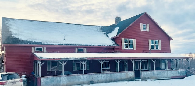 snow covered back of property with a porch