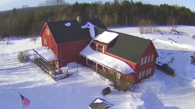 snowy aerial view featuring a wooded view