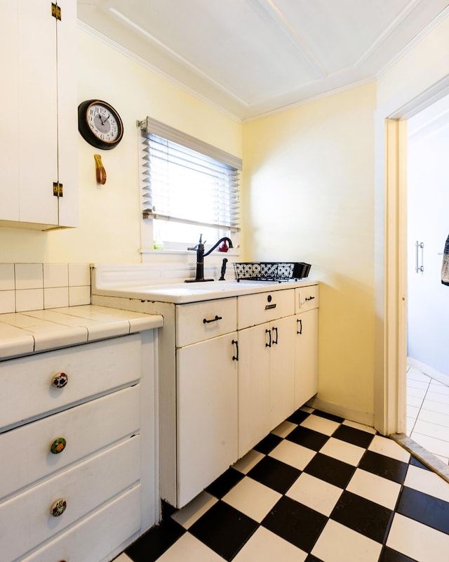 kitchen with white cabinetry, sink, crown molding, and tile countertops