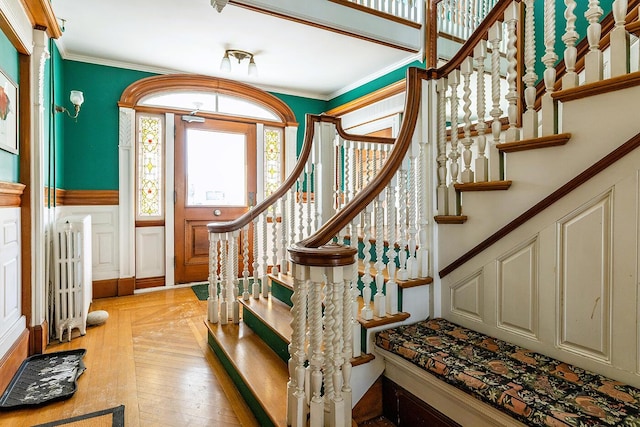 staircase featuring hardwood / wood-style floors, crown molding, and radiator heating unit