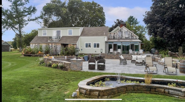 back of house featuring a lawn, a patio, a balcony, a chimney, and an outdoor hangout area