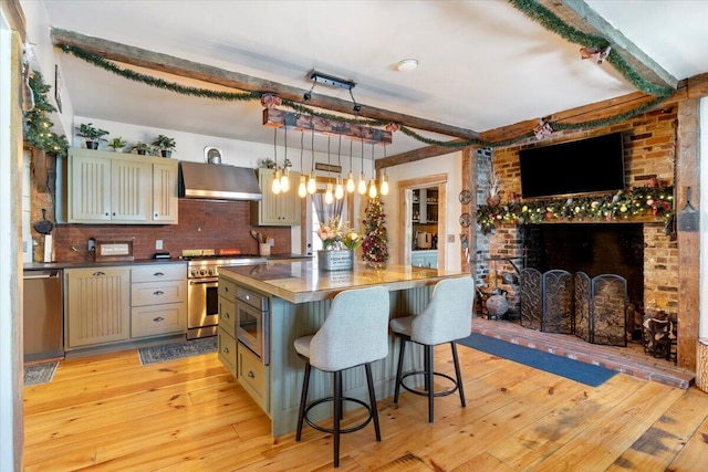 kitchen featuring dark countertops, wall chimney exhaust hood, a kitchen island, and stainless steel appliances