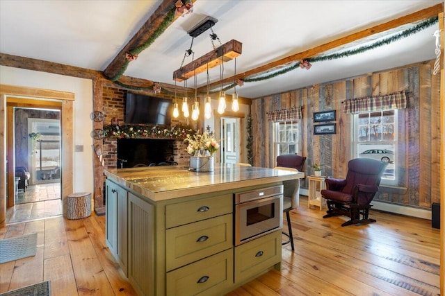 kitchen featuring beam ceiling, pendant lighting, a fireplace, and green cabinets