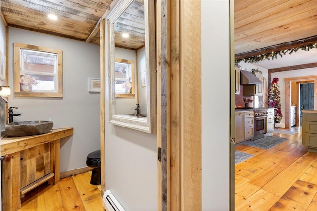 corridor featuring a baseboard heating unit, light wood-type flooring, wooden ceiling, and a sink