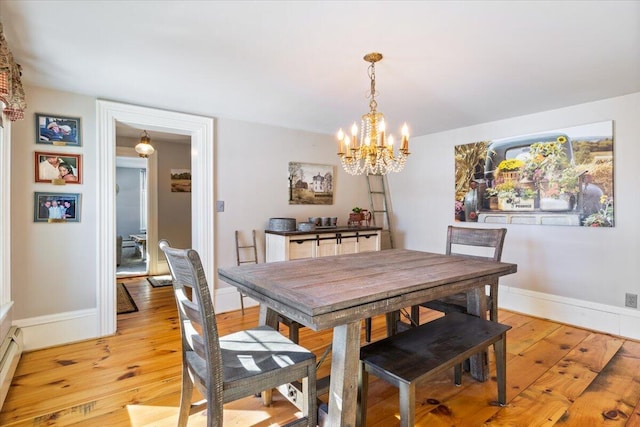 dining area with a chandelier, baseboard heating, baseboards, and light wood finished floors