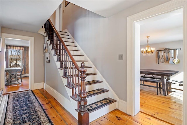 stairs with baseboards, a chandelier, and wood finished floors